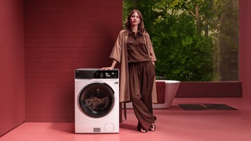 Woman standing next to washing machine.